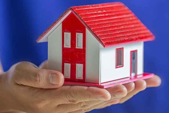 Human hands holding model of dream house, loans and investments Human hands holding model of dream house, loans and investments concept